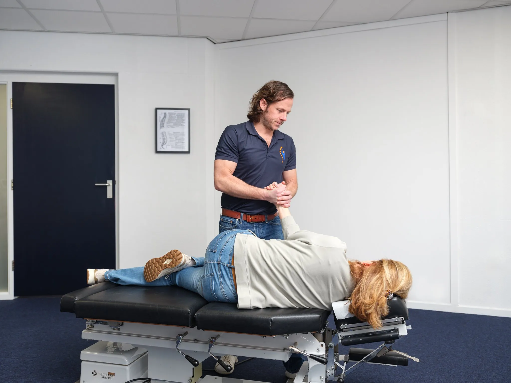 Chiropractor voert een polsbehandeling uit op een patiënt die op de behandeltafel ligt in de praktijk
