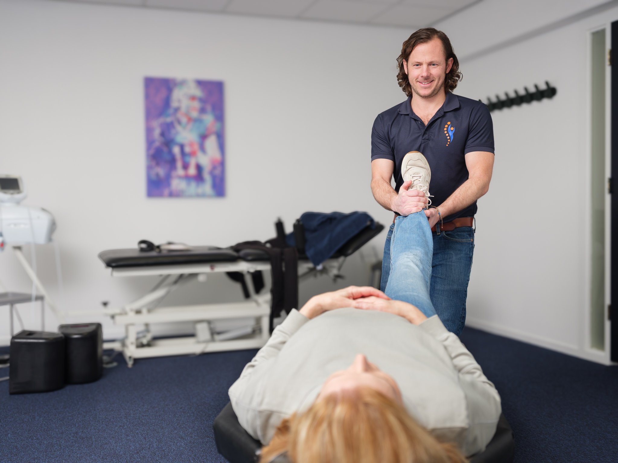 Chiropractor voert een beenbewegelijkheidstest uit bij een patiënte op de behandeltafel in de chiropraktijk